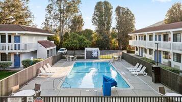 A rectangular pool with lounge chairs and a sign indicating no pets allowed.