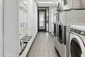 Een wasserette met meerdere wasmachines en een rij wasbakken aan de linkerkant.