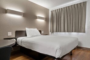 Een hotelkamer met een bed, een bureau en een raam met gordijnen.