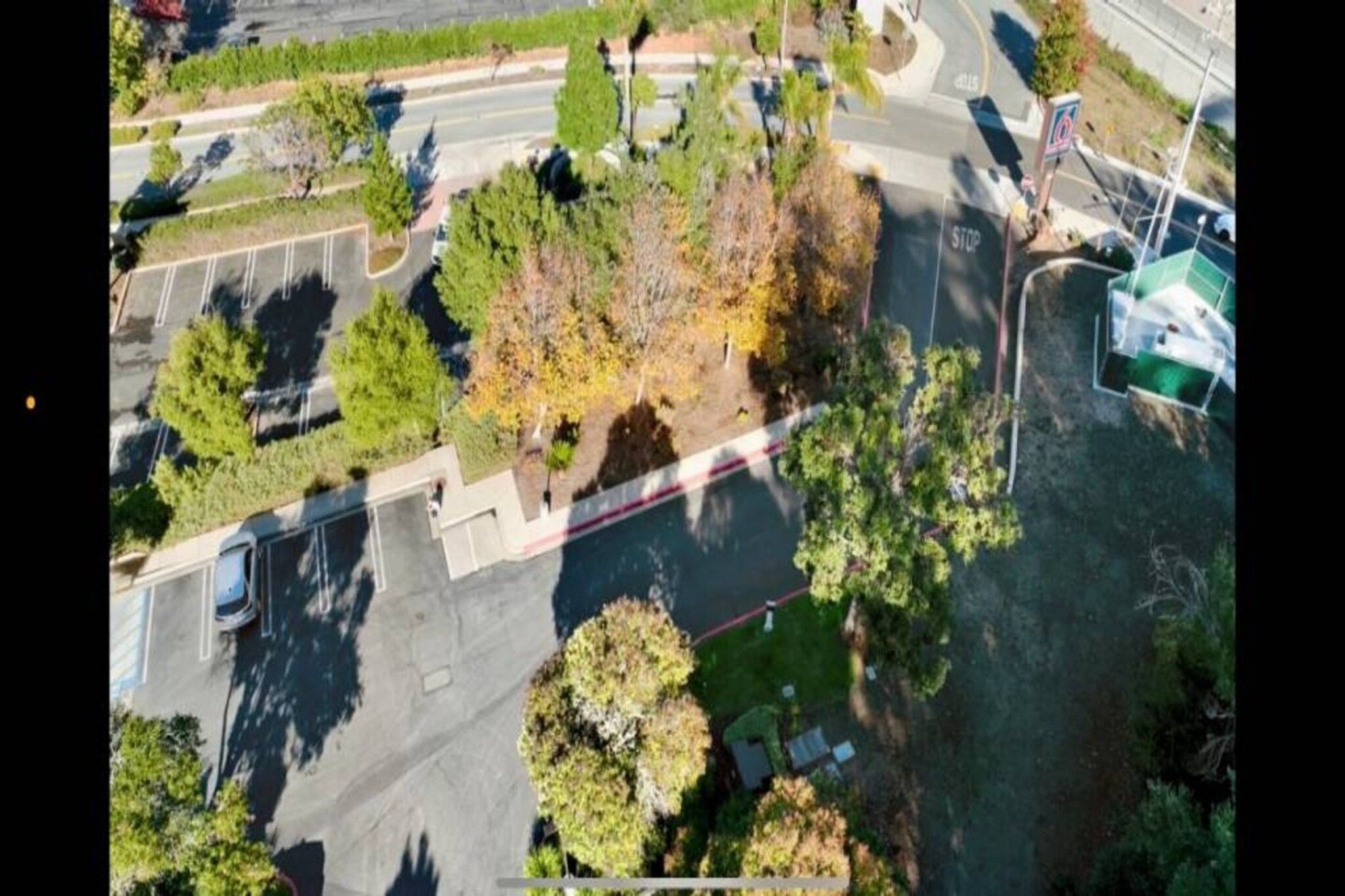 Vue aérienne d’un parking bordé d’arbres et traversé par une route.