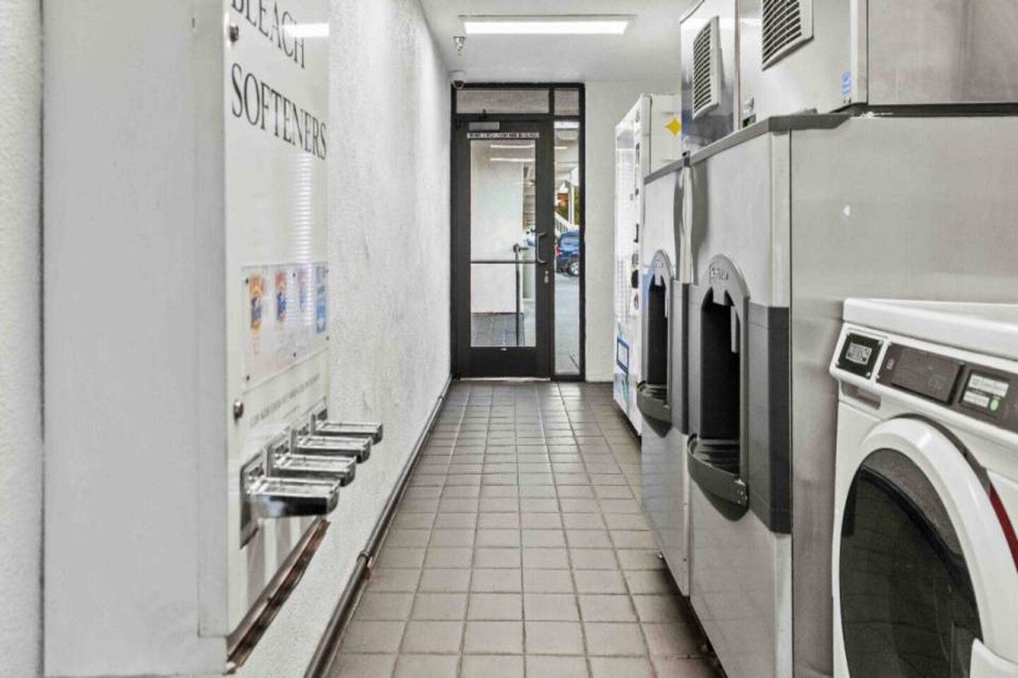A laundry facility with multiple washing machines and a row of sinks on the left.