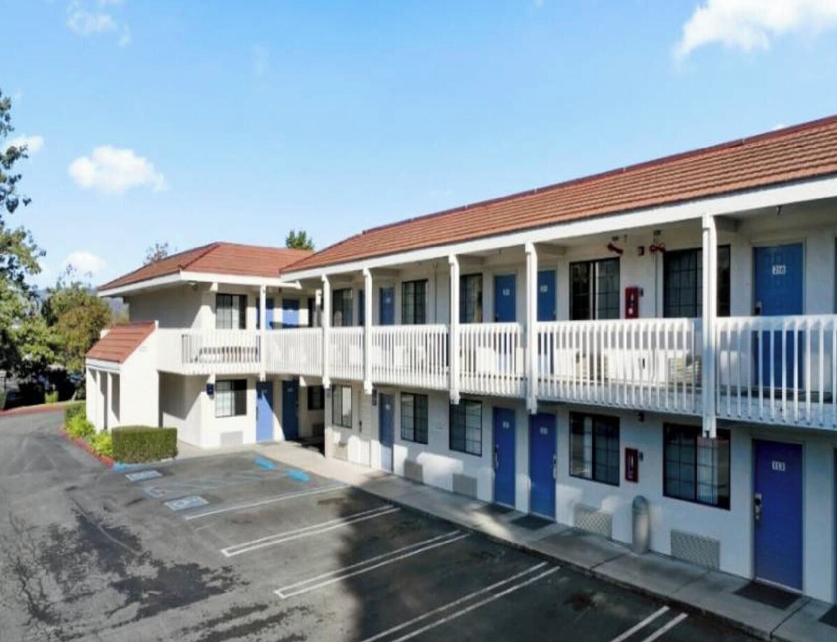 A motel with multiple rooms, a parking lot, and a clear sky.
