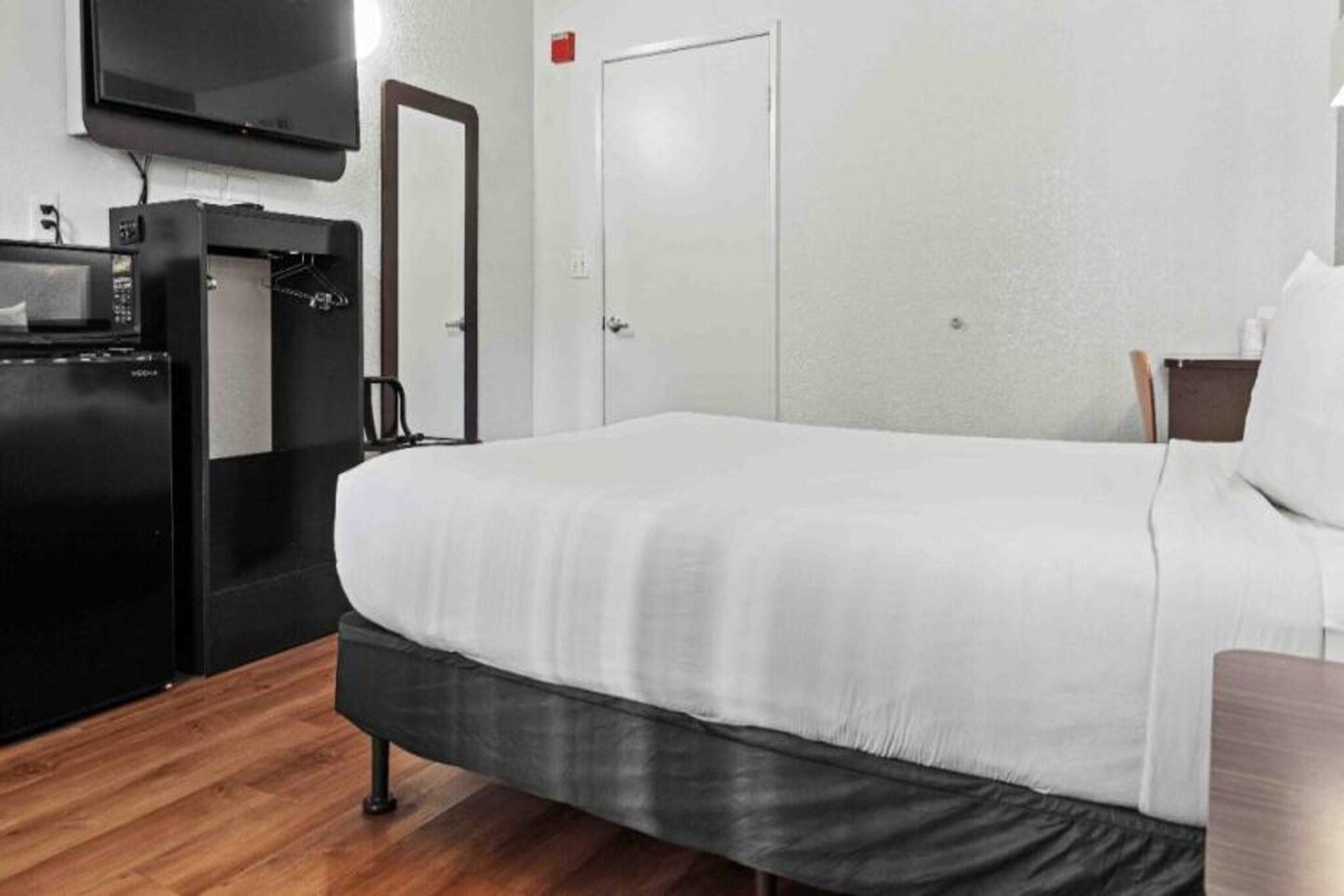 A hotel room with a bed, a television, a microwave, and a wardrobe.