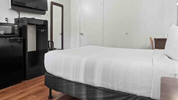 A hotel room with a bed, a television, a microwave, and a wardrobe.
