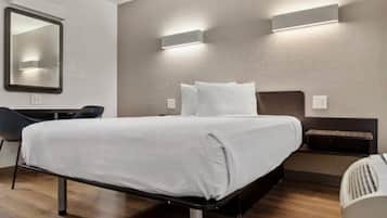 A modern hotel room with a bed, bedside tables, a chair, and a mirror.