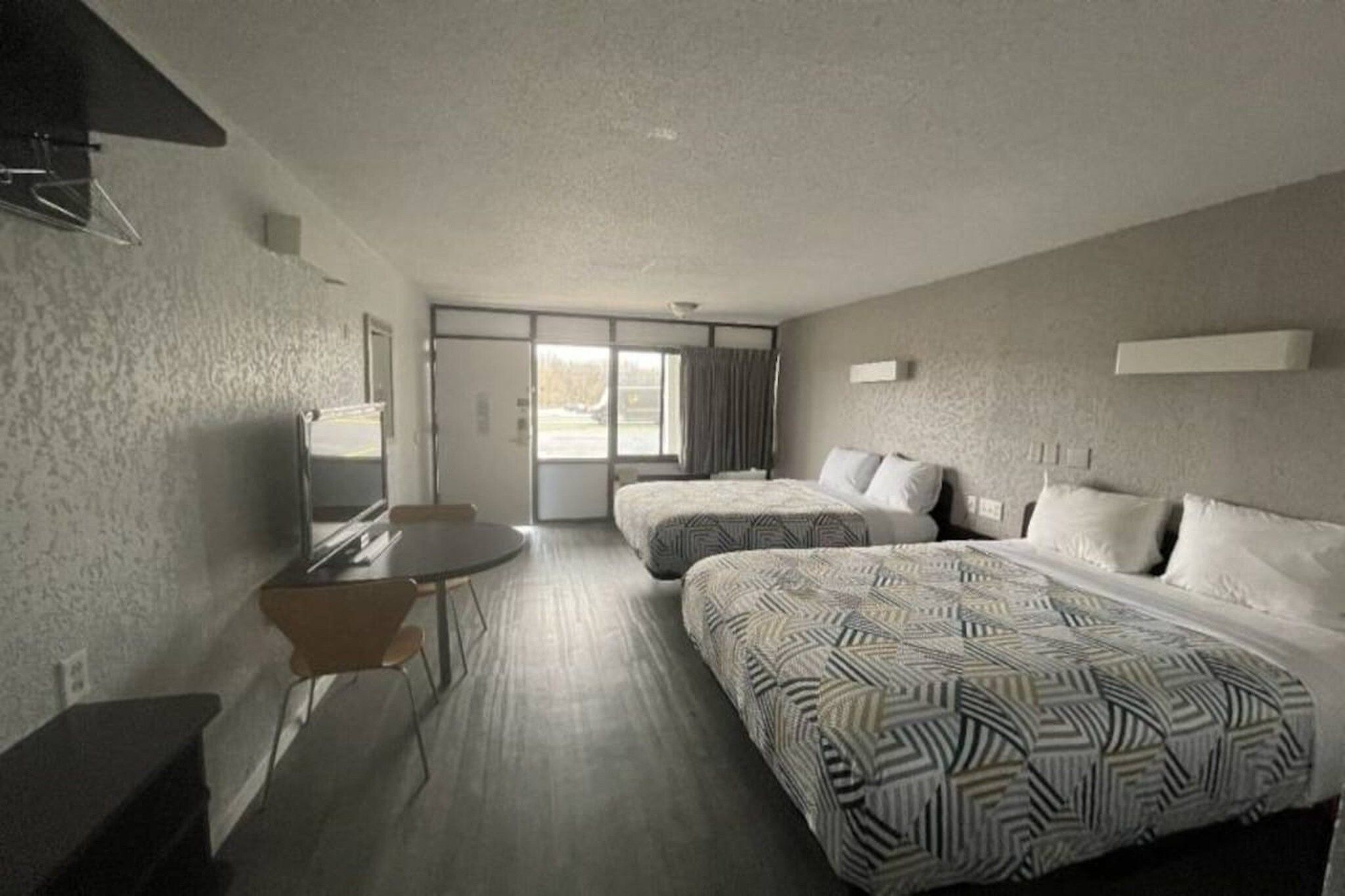 Ein Hotelzimmer mit zwei Betten, einem Schreibtisch und einem Stuhl.