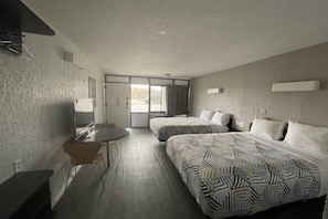 Ein Hotelzimmer mit zwei Betten, einem Schreibtisch und einem Stuhl.