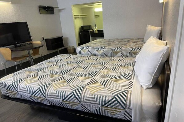 Habitació d'hotel amb dos llits, una taula de treball, una cadira i una televisió.