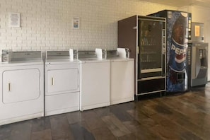 Ein Waschraum mit vier wei ßen Waschmaschinen und einem Kühlschrank mit Pepsi-Logo.