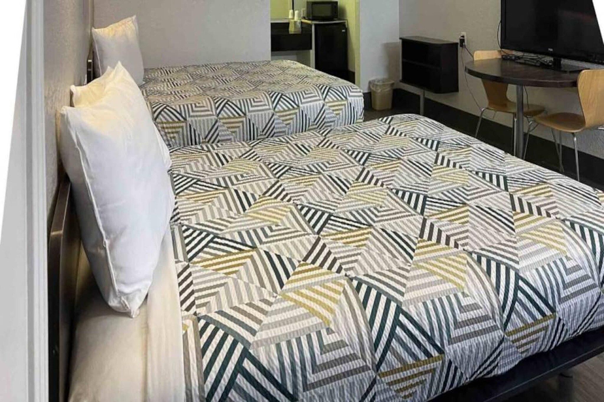 Een hotelkamer met een bed, een televisie, een bureau en een stoel.