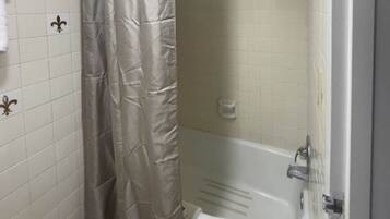 Ein Badezimmer mit einer Badewanne, einer Duschvorhang und Fliesenwänden.