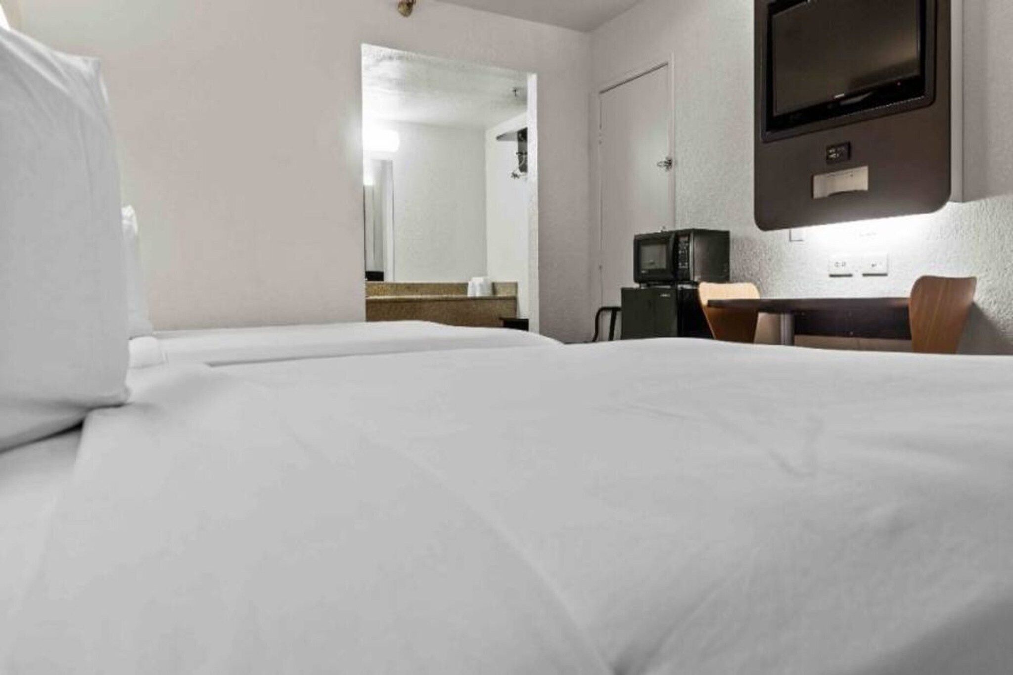 A hotel room with a bed, a television, a desk, and a chair.