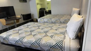 Une chambre d’hôtel avec deux lits, un bureau, une chaise et un téléviseur.
