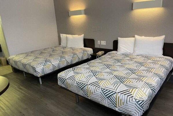 Two twin beds with patterned bedding, a bedside table with a phone, and wall-mounted lighting.