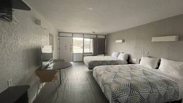 Een hotelkamer met twee bedden, een bureau en een stoel.