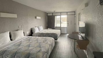 Ein Hotelzimmer mit zwei Betten, einem kleinen Tisch und einem Fernseher.