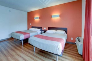 Habitación de hotel con dos camas, suelo de madera y cortina roja.