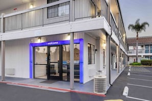 A hotel entrance with a 'welcome' sign, a covered entrance, and a parking lot.