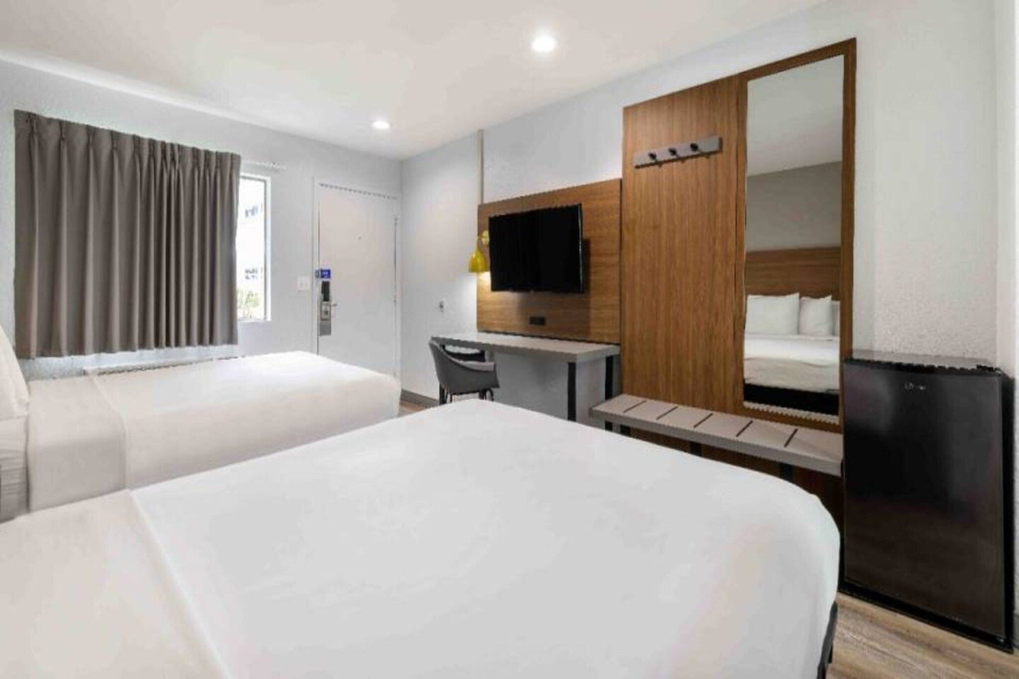 Une chambre d’hôtel avec deux lits, un bureau, une télévision et une armoire.