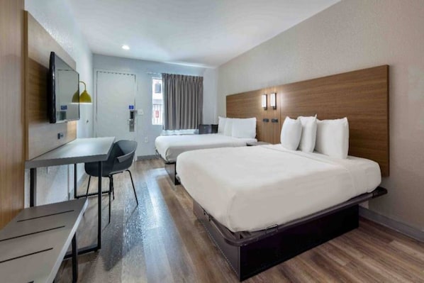 A hotel room with a bed, a desk, and a chair.