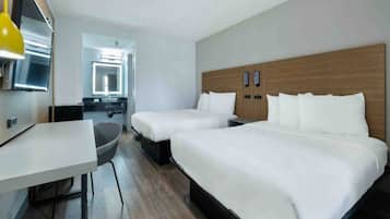 A hotel room with two beds, a desk, a chair, and a television.
