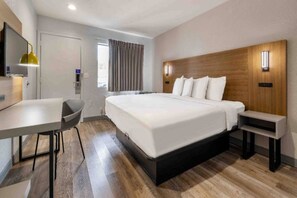 Een hotelkamer met een bed, een bureau, een stoel en een klein tafeltje.