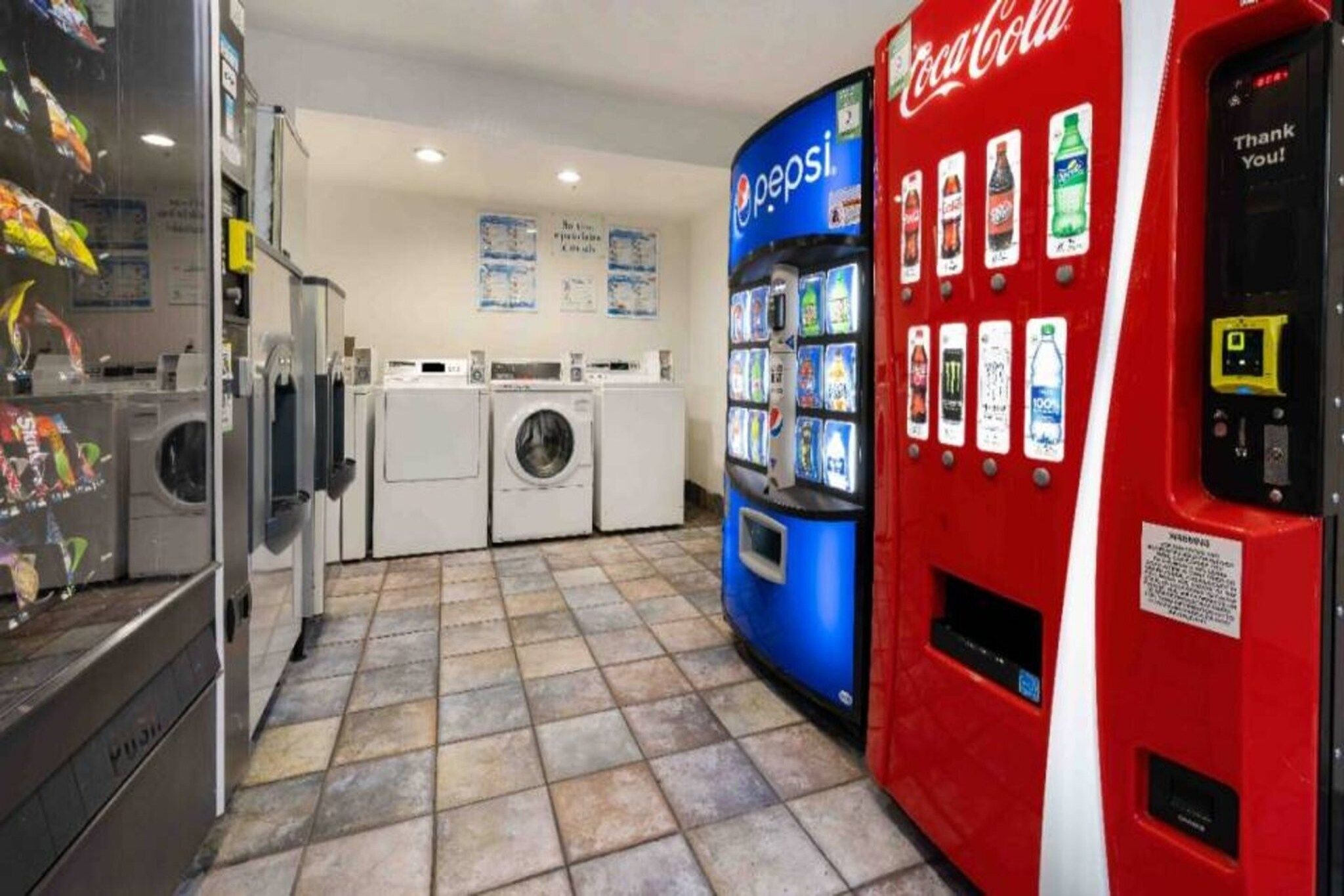 A laundromat with washing machines, a Pepsi vending machine, and a Coca-Cola vending machine.