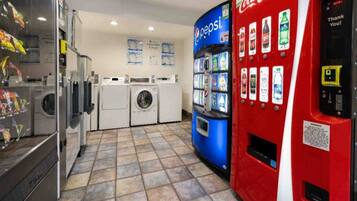 A laundromat with washing machines, a Pepsi vending machine, and a Coca-Cola vending machine.