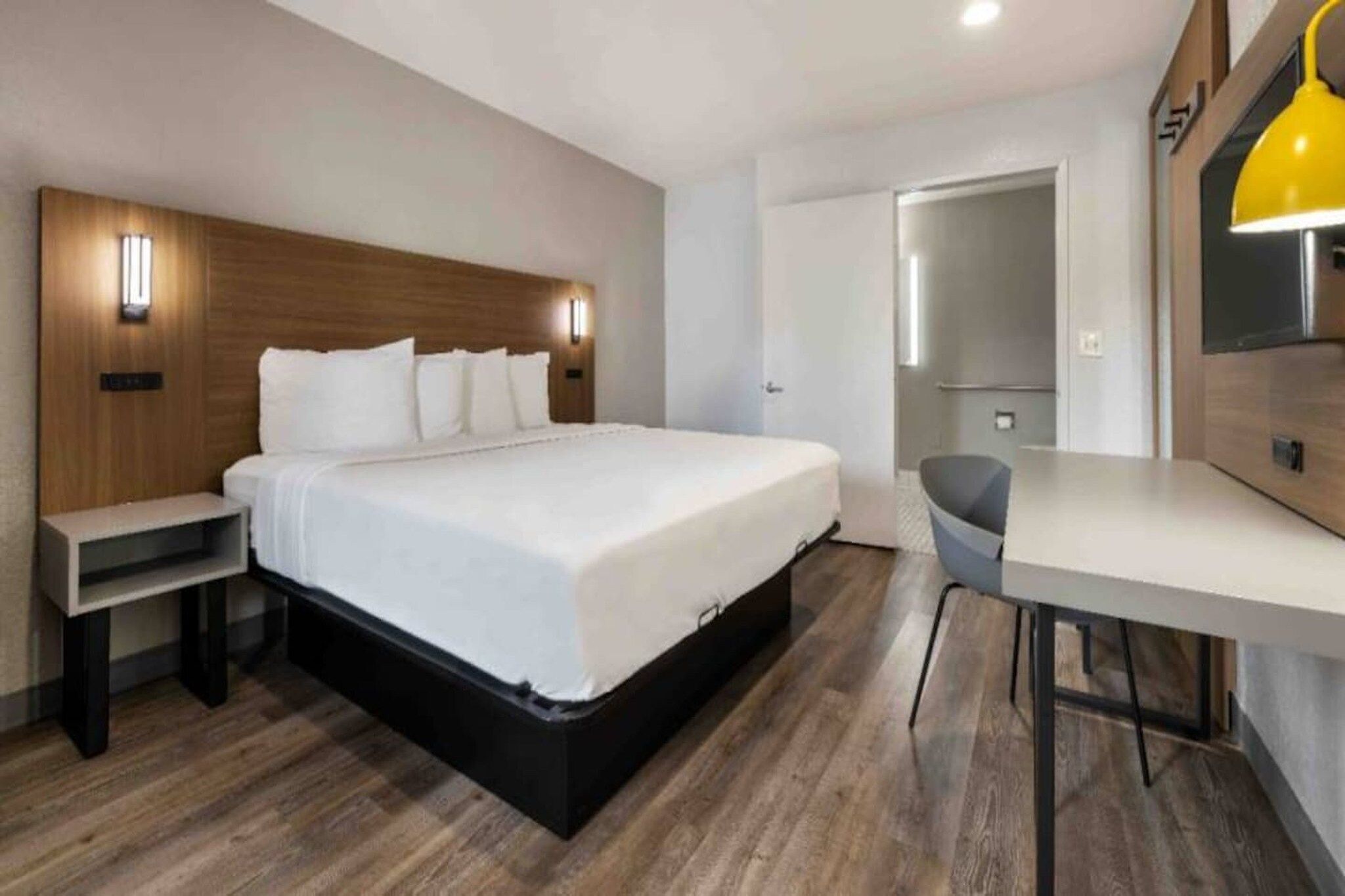 Una habitación de hotel moderna con una cama grande, mesitas de noche, un escritorio y una silla.