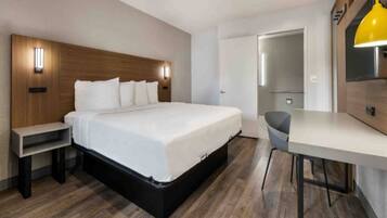 Una habitación de hotel moderna con una cama grande, mesitas de noche, un escritorio y una silla.