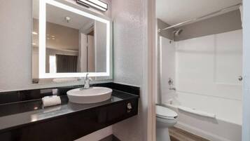 A modern bathroom with a large mirror, a sink, and a shower area.