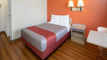 A hotel room with a bed, bedside table, and a chair.