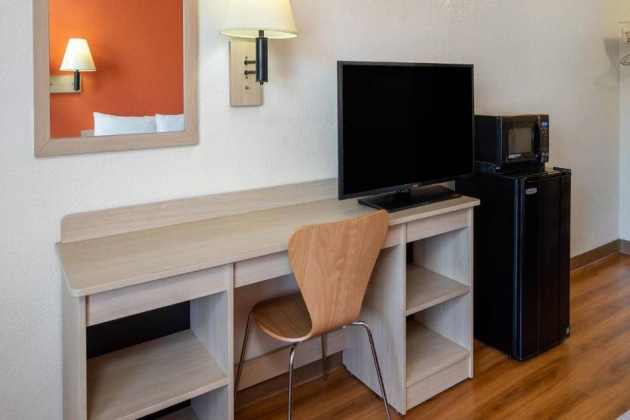 Ein Hotelzimmer mit einem Holztisch, einem Fernseher, einer Mikrowelle und einem Stuhl.