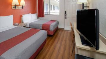 Een hotelkamer met twee bedden, een televisie en een raam met gordijnen.
