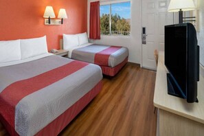 Ein Hotelzimmer mit zwei Betten, einem Fernseher, einem Fenster mit Blick und einer Tür.