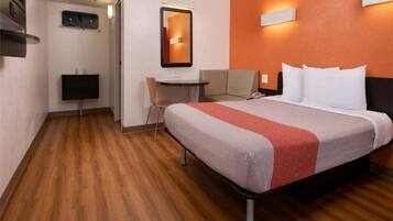 A hotel room with a bed, a desk, a chair, a TV, and a mirror.