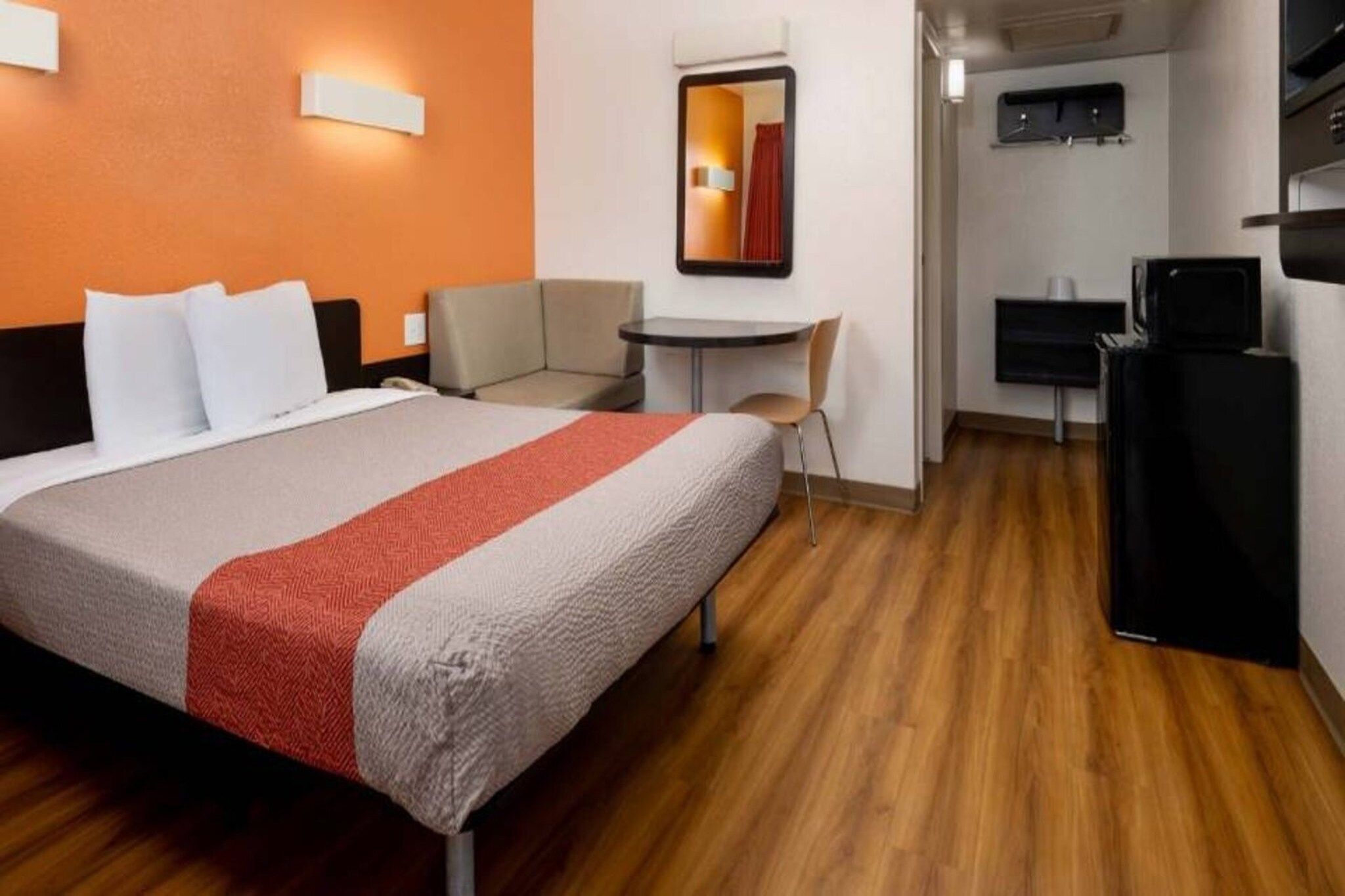 A hotel room with a bed, a desk, a chair, and a television.