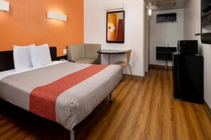 Une chambre d’hôtel avec un lit, un bureau, une chaise et un téléviseur.