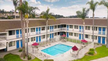 A motel with a swimming pool, multiple balconies, and palm trees.