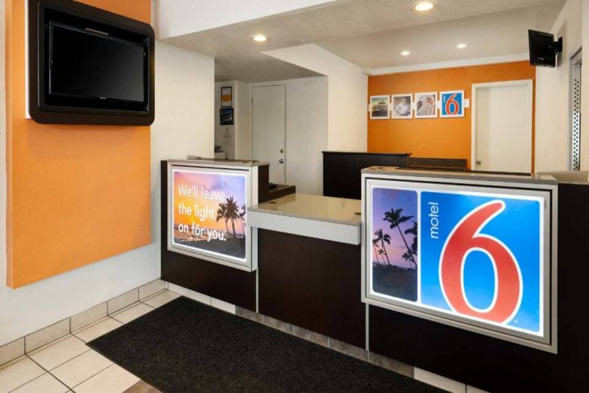 A hotel reception area with a digital display, a reception desk, and a wall-mounted TV.