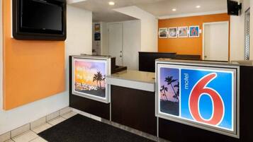 A hotel reception area with a digital display, a reception desk, and a wall-mounted TV.