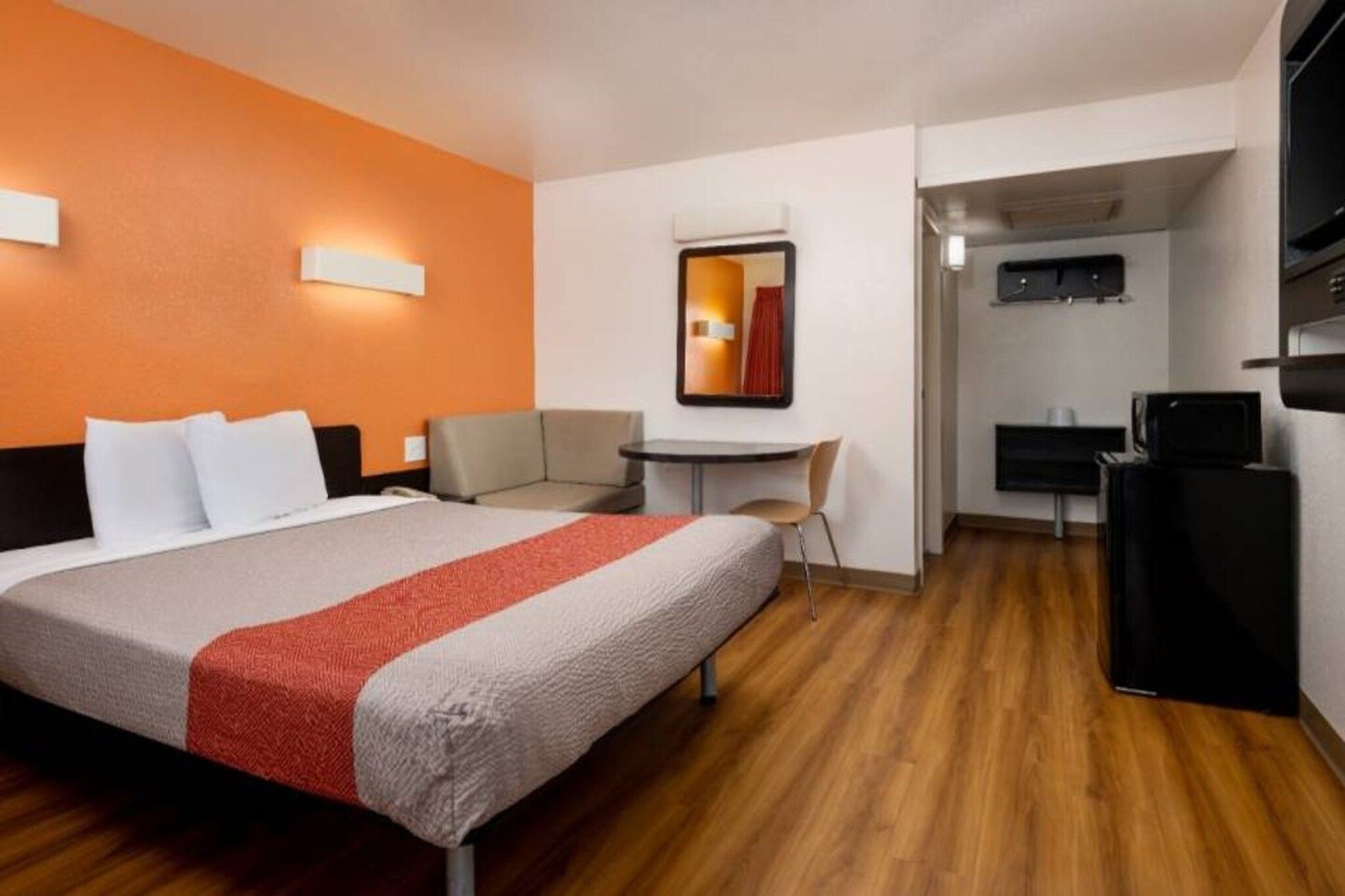 Ein Hotelzimmer mit einem Bett, einem Schreibtisch, einem Sessel, einem Fernseher und einer Mikrowelle.