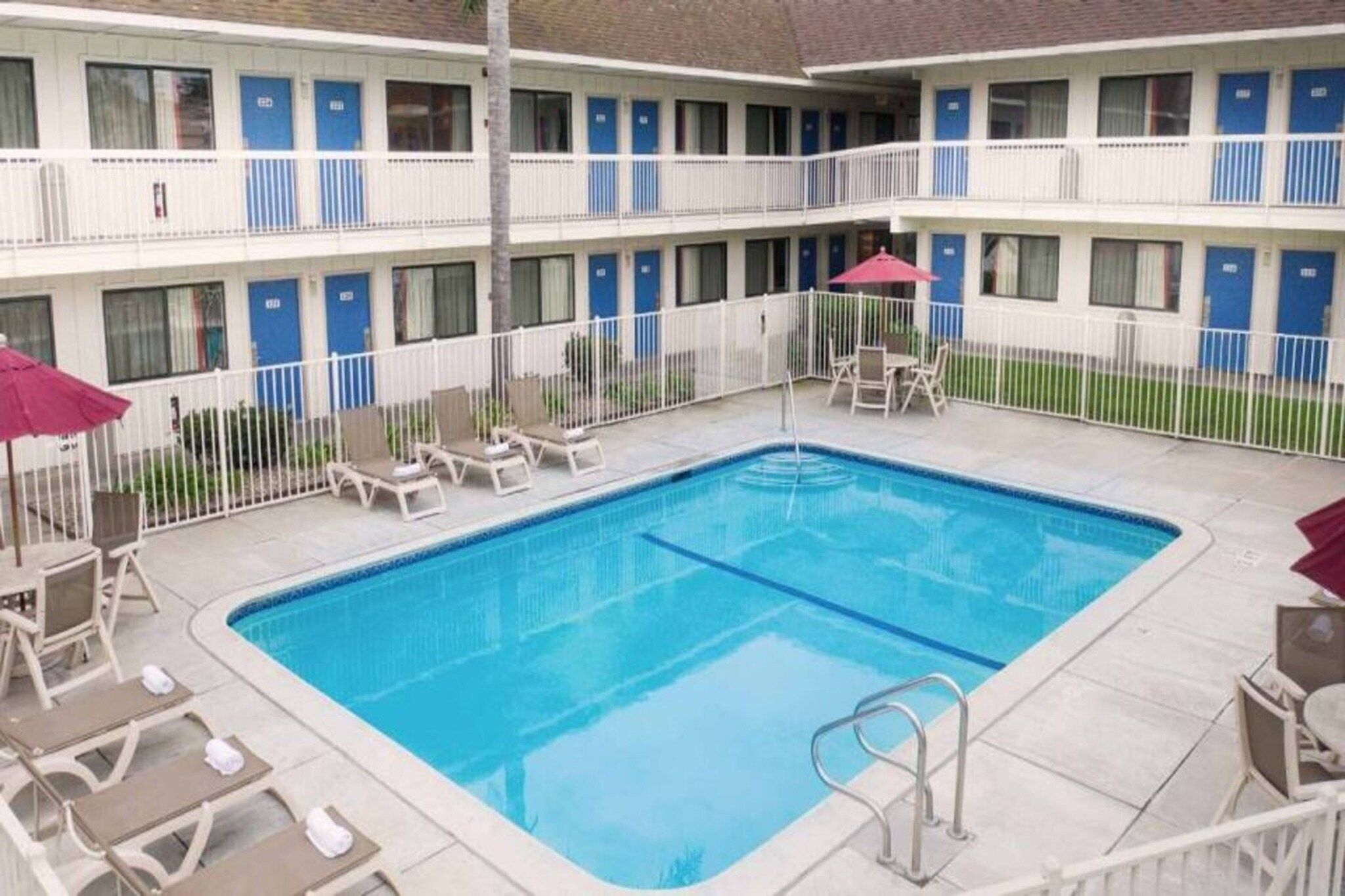 A hotel with a swimming pool, multiple balconies, and outdoor seating.