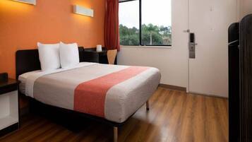 Una camera d'albergo con un letto, un comodino, una finestra con tende e una porta.
