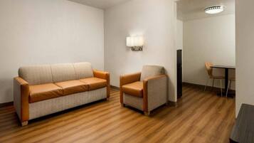 A room with a sofa and a chair, a table, and a wall-mounted light fixture.