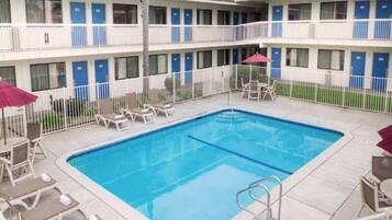 A hotel with a swimming pool, multiple balconies, and outdoor seating.