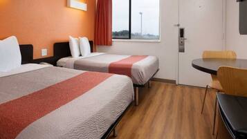 A hotel room with two beds, a window with a view, a desk, and a chair.