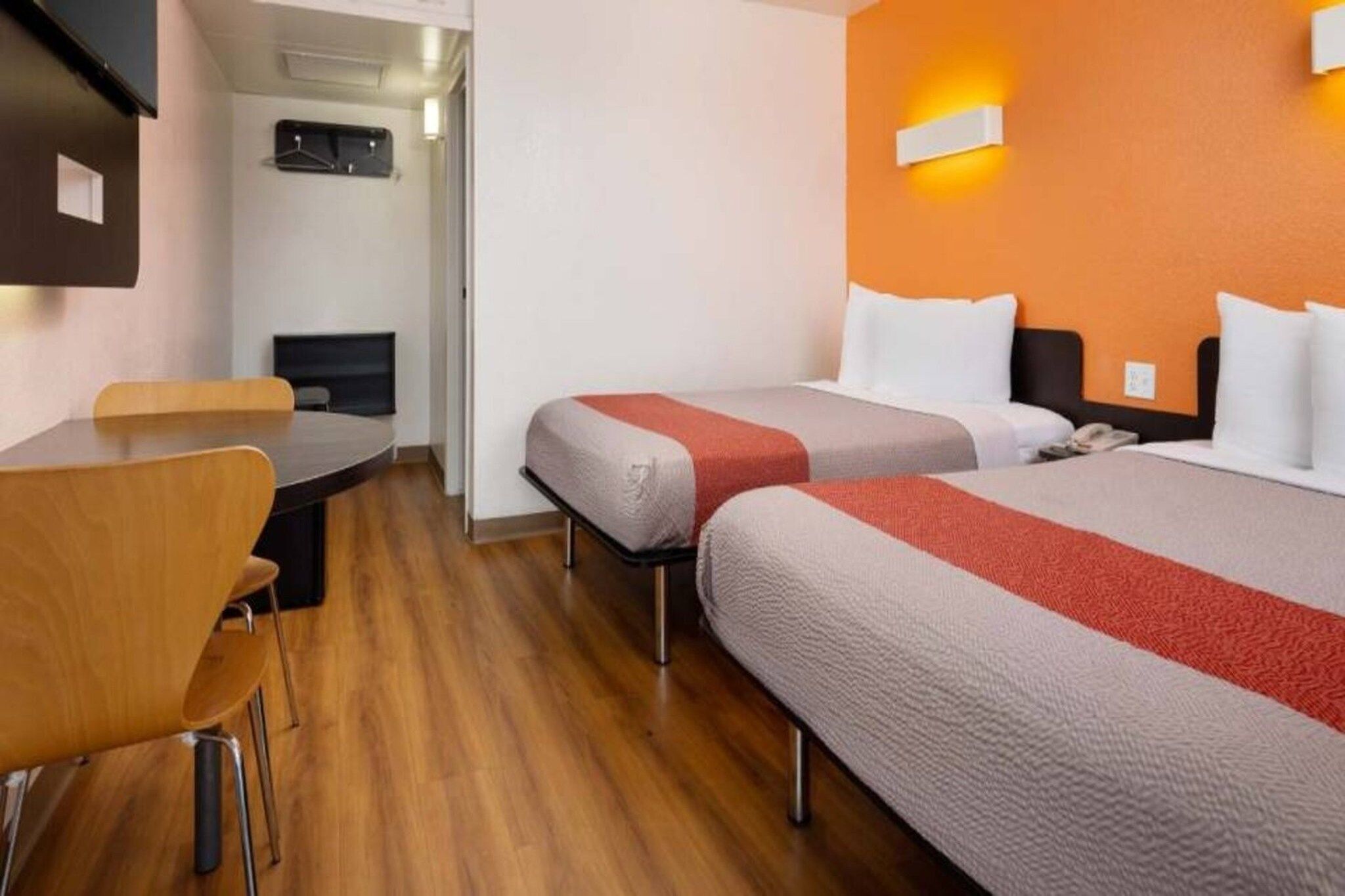 A hotel room with two beds, a desk, and a chair.