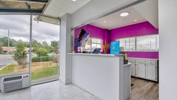 Un'area di accoglienza con una porta in vetro che dà sull'esterno, un bancone con un computer e una parete d'accento color viola.