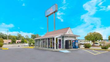 A motel with a large sign, a drive-through window, and a Pepsi vending machine.
